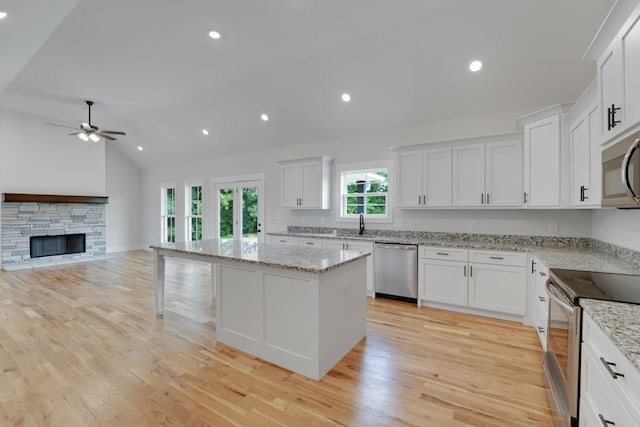 kitchen with lofted ceiling, a center island, stainless steel appliances, and light wood-type flooring