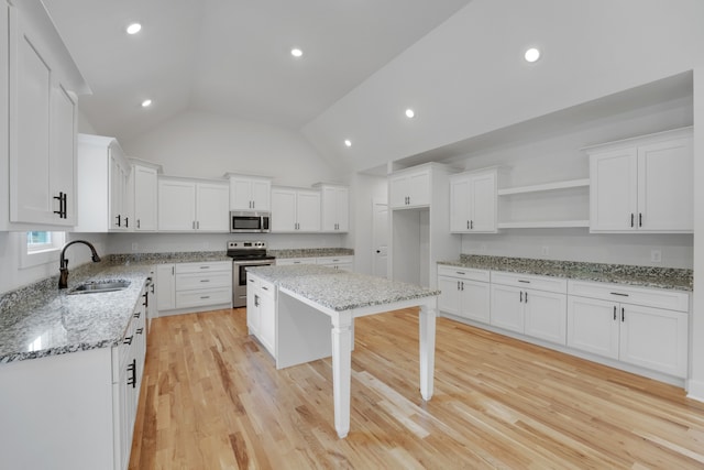 kitchen featuring lofted ceiling, light hardwood / wood-style flooring, stainless steel appliances, sink, and white cabinetry