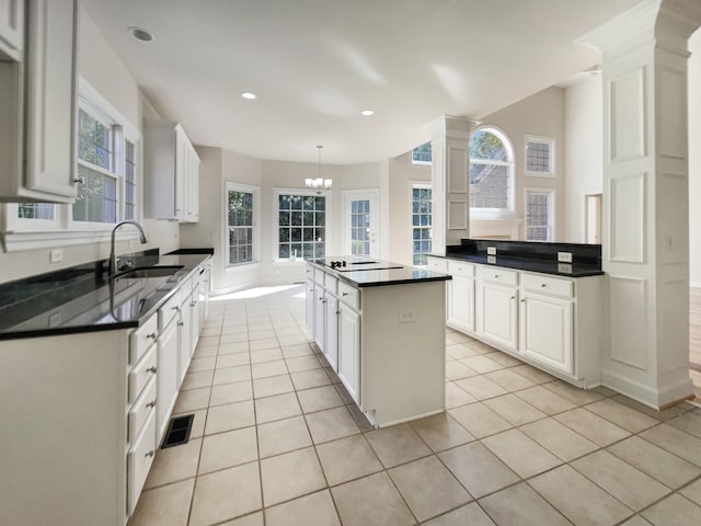 kitchen with sink, a kitchen island, pendant lighting, white cabinets, and light tile patterned floors