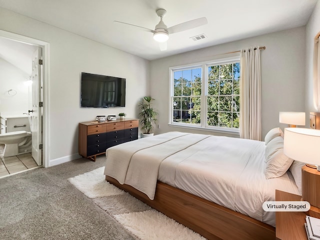 bedroom featuring ensuite bath, light colored carpet, and ceiling fan