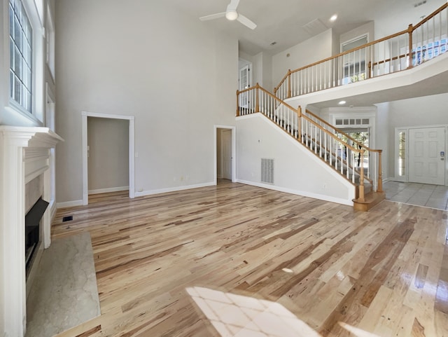 living room with light hardwood / wood-style floors, a high ceiling, and ceiling fan