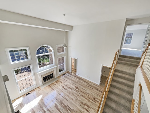 living room featuring a towering ceiling, light hardwood / wood-style floors, and ceiling fan