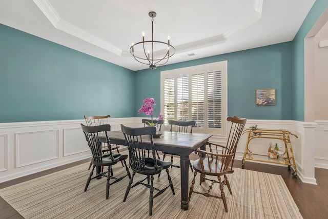 dining area featuring crown molding, a notable chandelier, a tray ceiling, and dark hardwood / wood-style flooring