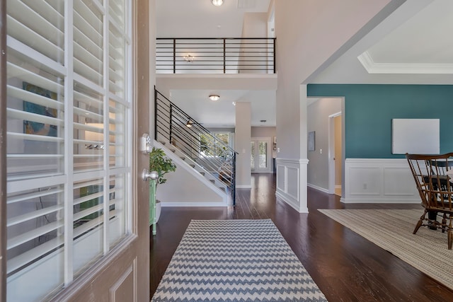 foyer entrance with ornamental molding, ornate columns, dark hardwood / wood-style floors, and a towering ceiling