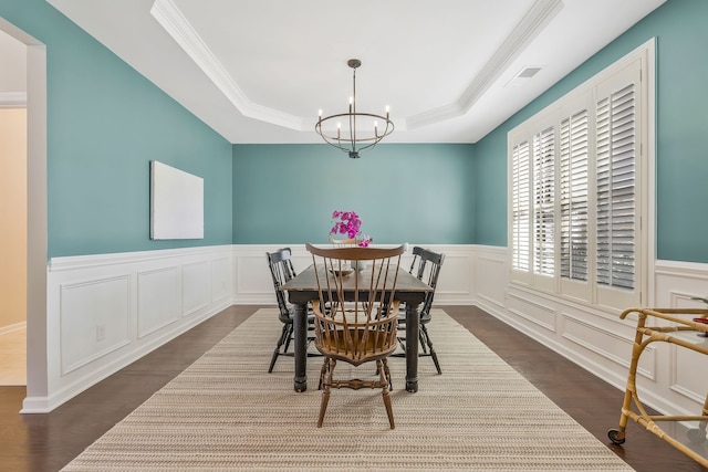 dining room featuring a notable chandelier, ornamental molding, a raised ceiling, and dark hardwood / wood-style floors