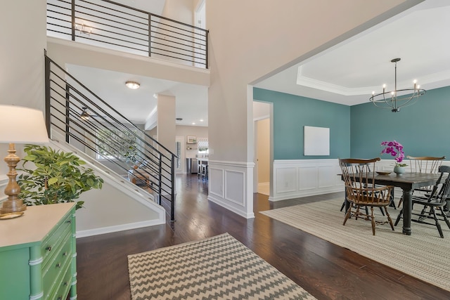 foyer entrance featuring a high ceiling, crown molding, dark hardwood / wood-style flooring, and an inviting chandelier