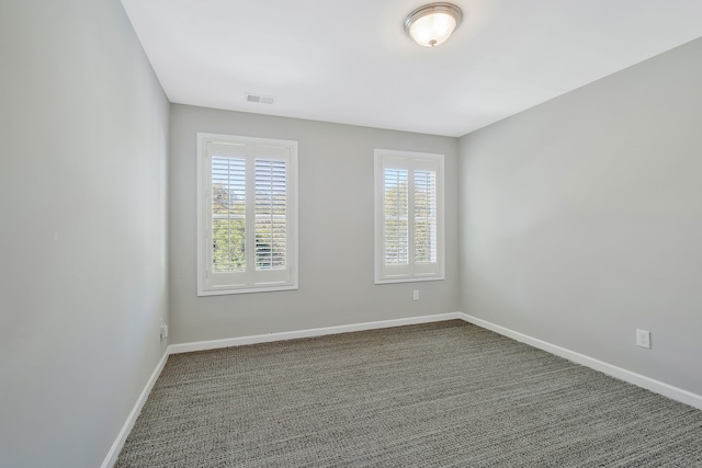 unfurnished room with a healthy amount of sunlight and dark carpet