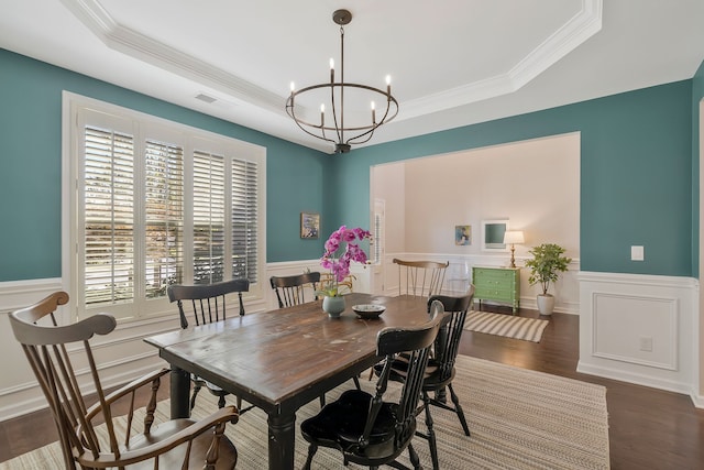 dining space featuring ornamental molding, a chandelier, dark hardwood / wood-style floors, and a raised ceiling