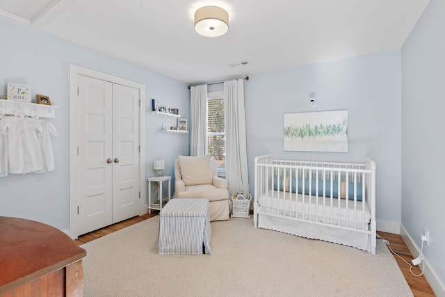 bedroom with a closet, a nursery area, and wood-type flooring