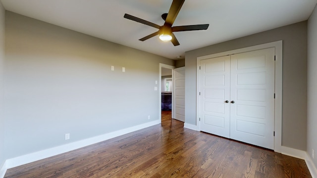 unfurnished bedroom with dark wood-type flooring, a closet, and ceiling fan