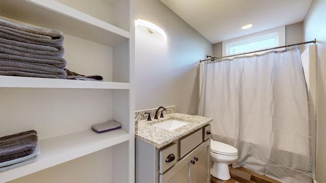 bathroom with toilet, hardwood / wood-style floors, walk in shower, and vanity