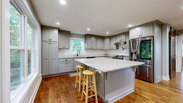 kitchen featuring tasteful backsplash, appliances with stainless steel finishes, a breakfast bar, hardwood / wood-style flooring, and sink