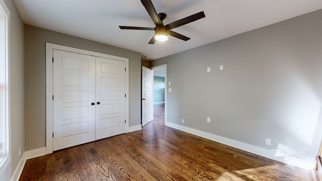 unfurnished bedroom with a closet, dark hardwood / wood-style floors, and ceiling fan