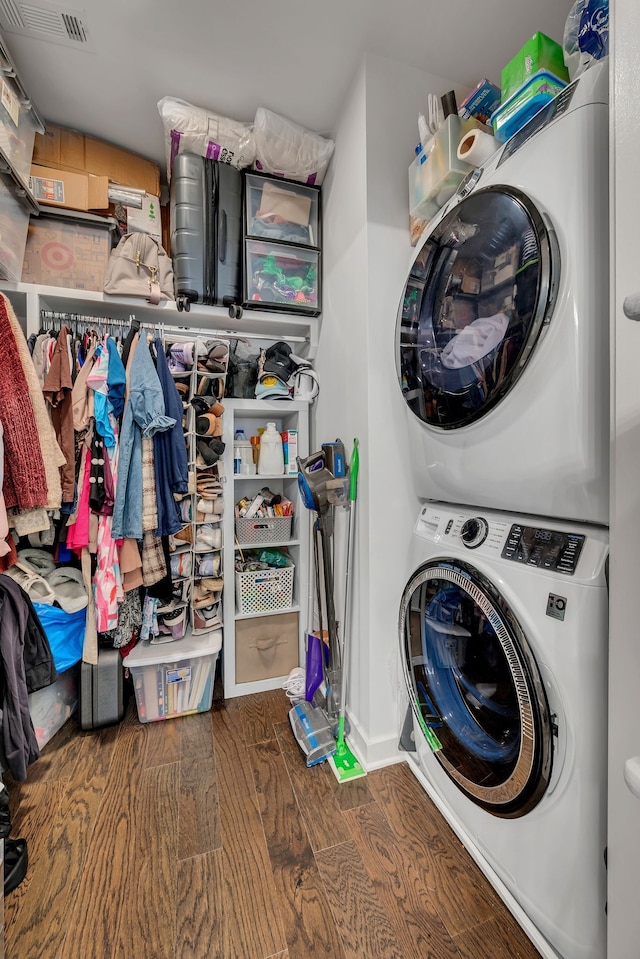 clothes washing area featuring stacked washer and dryer and dark hardwood / wood-style flooring