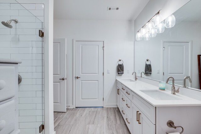 bathroom with vanity, wood-type flooring, and tiled shower