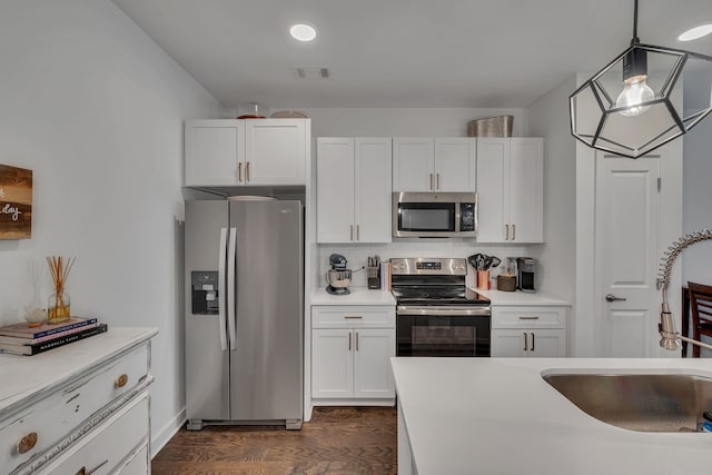 kitchen with sink, appliances with stainless steel finishes, hanging light fixtures, and white cabinetry