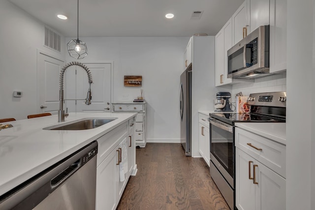 kitchen featuring white cabinets, hanging light fixtures, appliances with stainless steel finishes, dark wood-type flooring, and sink