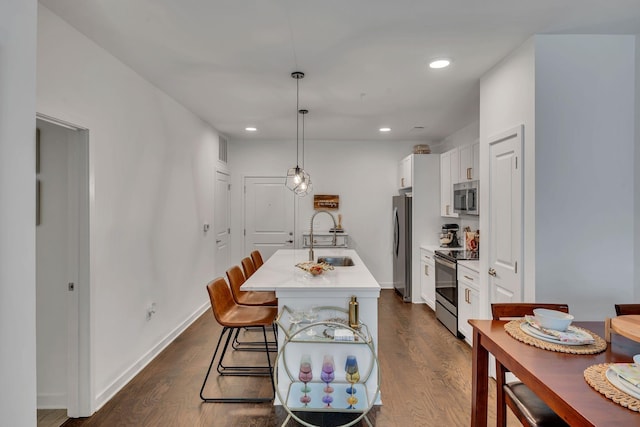 1677 54th Ave N Unit 218, Nashville, TN 37209 - kitchen featuring appliances with stainless steel finishes, a sink, an island with sink, dark wood-style floors, and white cabinets