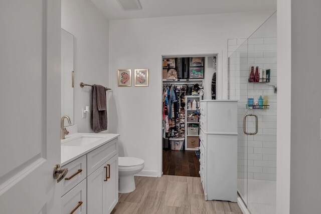 bathroom featuring vanity, an enclosed shower, hardwood / wood-style floors, and toilet