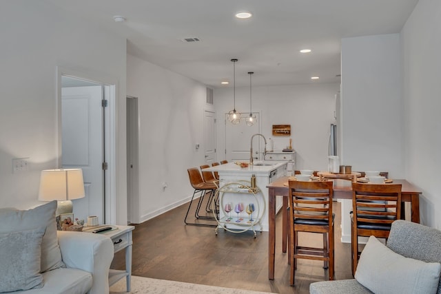 dining space featuring sink, dark hardwood / wood-style flooring, and a chandelier