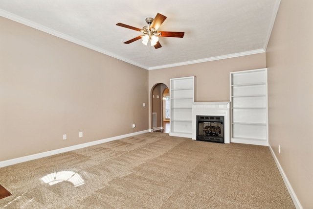 unfurnished living room featuring baseboards, carpet, arched walkways, and crown molding