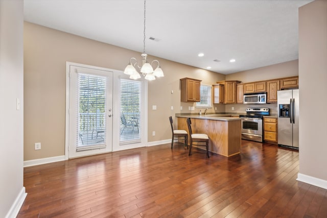 kitchen with appliances with stainless steel finishes, dark wood finished floors, a wealth of natural light, and baseboards