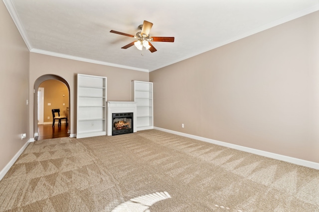 unfurnished living room featuring baseboards, arched walkways, ornamental molding, and light colored carpet