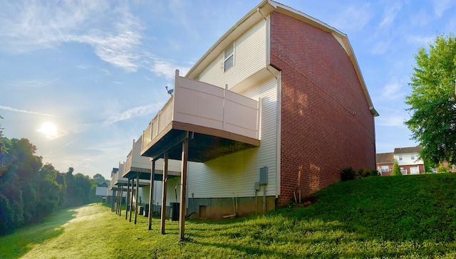 back of property with a balcony, a yard, and brick siding