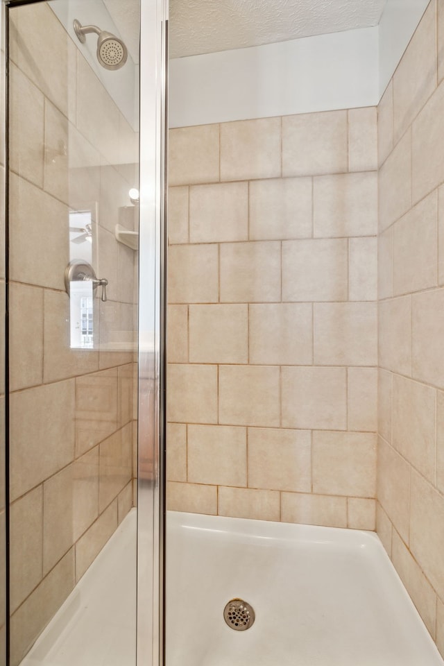 full bathroom featuring a textured ceiling and a shower stall