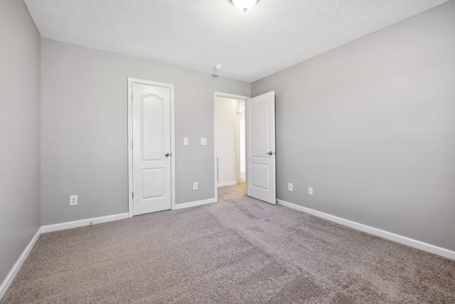 unfurnished bedroom with a textured ceiling, carpet, and baseboards