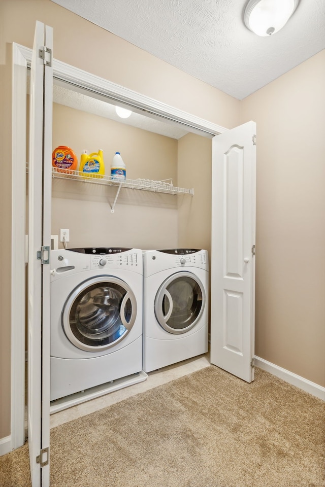 washroom featuring laundry area, carpet flooring, washer and clothes dryer, and a textured ceiling