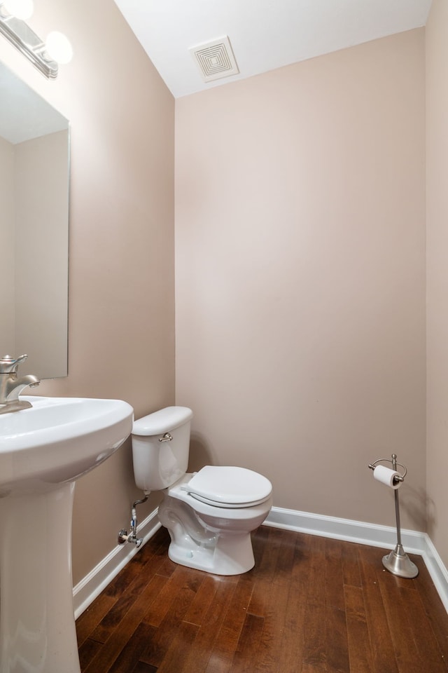 bathroom with baseboards, visible vents, hardwood / wood-style floors, and toilet