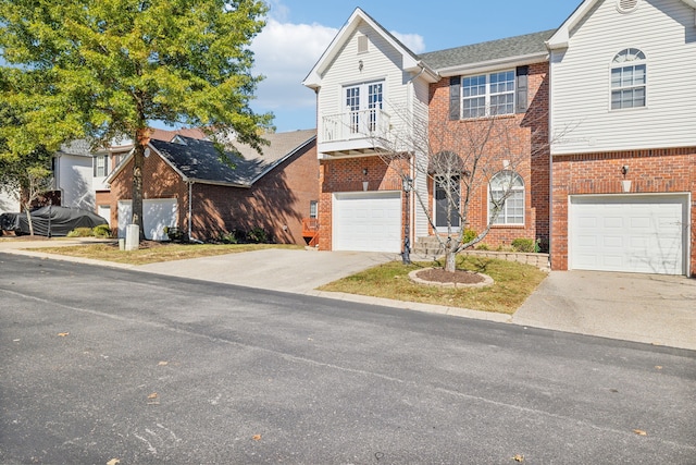 view of front of home featuring a garage, concrete driveway, brick siding, and a balcony