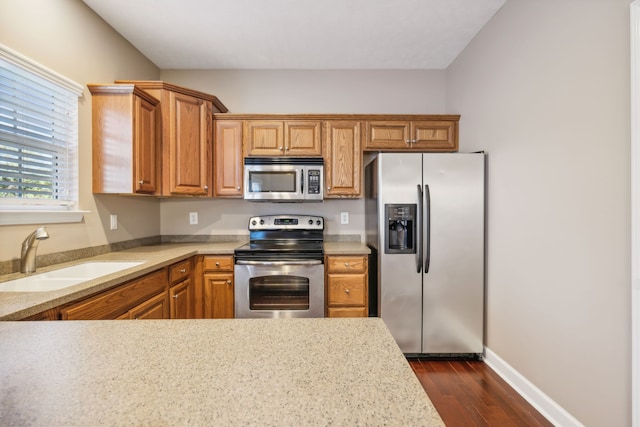 kitchen featuring dark wood finished floors, stainless steel appliances, a sink, and light countertops