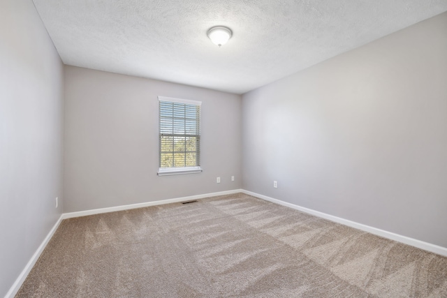 carpeted spare room featuring visible vents, a textured ceiling, and baseboards