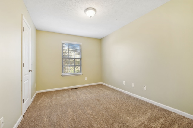 carpeted empty room with visible vents, a textured ceiling, and baseboards