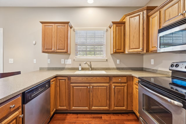 kitchen featuring appliances with stainless steel finishes, dark wood-style flooring, light countertops, and a sink