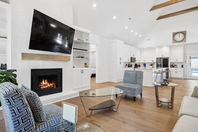 living room with sink, high vaulted ceiling, and light hardwood / wood-style flooring