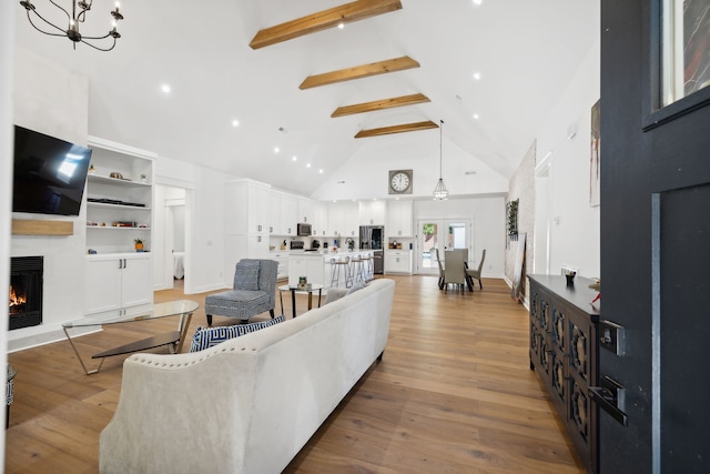 living room with beam ceiling, high vaulted ceiling, light hardwood / wood-style flooring, and a fireplace