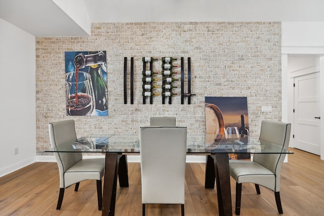 dining room featuring hardwood / wood-style floors and brick wall