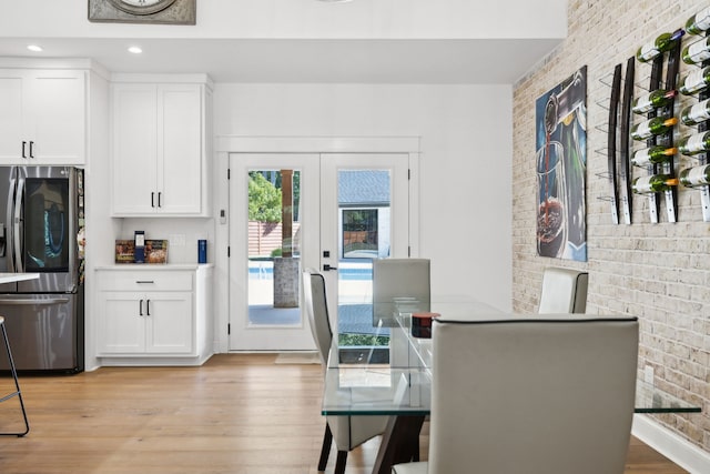 dining space featuring french doors, light hardwood / wood-style floors, and brick wall