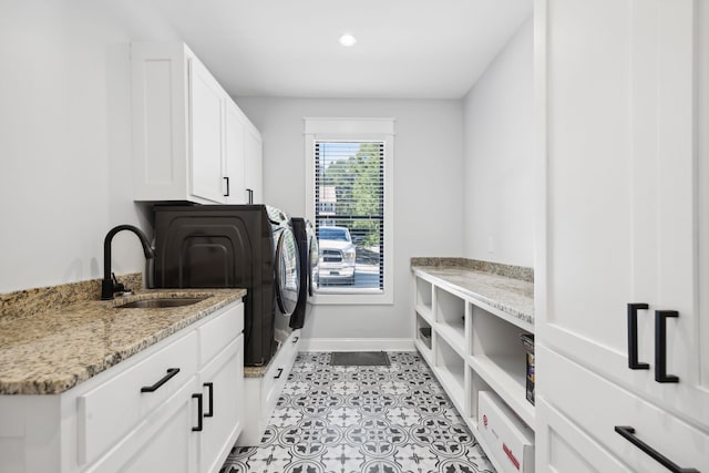 clothes washing area with cabinets, sink, washing machine and dryer, and light tile patterned floors