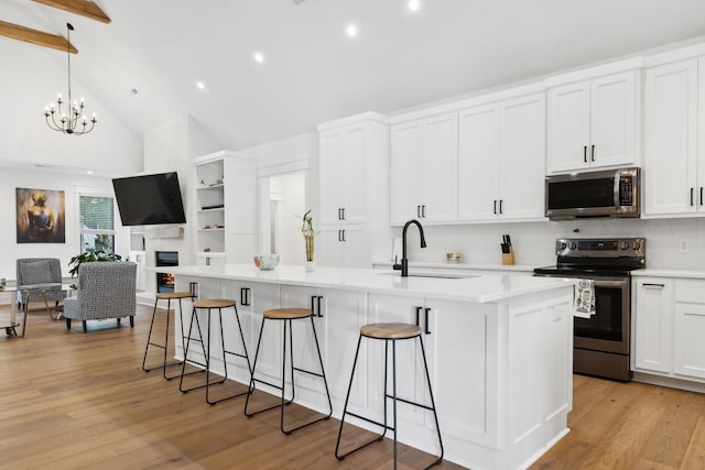 kitchen featuring sink, a kitchen island with sink, stainless steel appliances, and white cabinets