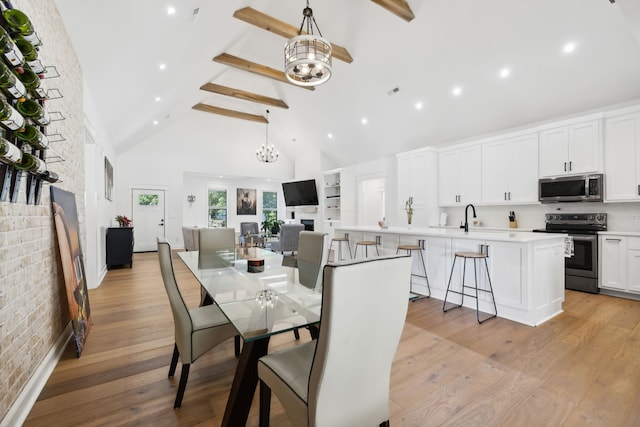 dining room with beamed ceiling, brick wall, high vaulted ceiling, and light hardwood / wood-style floors