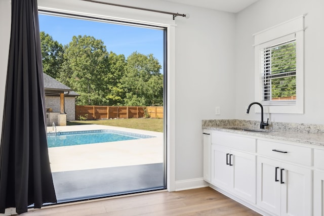 doorway to outside with sink, light wood-type flooring, and a healthy amount of sunlight