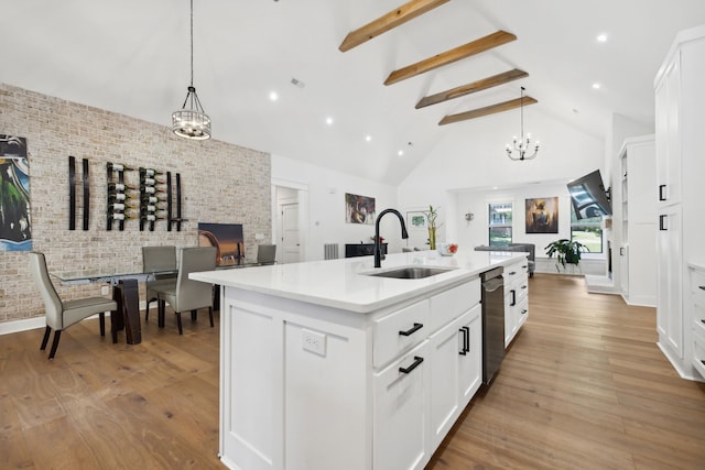 kitchen with an island with sink, hanging light fixtures, white cabinets, and light hardwood / wood-style floors