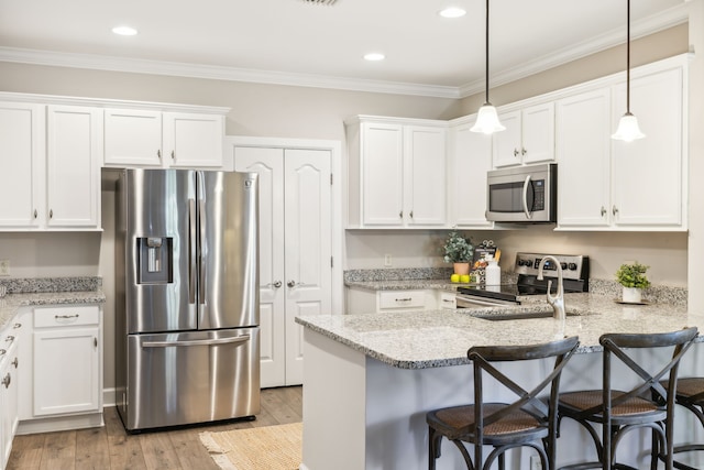 kitchen featuring kitchen peninsula, white cabinets, a kitchen breakfast bar, light hardwood / wood-style floors, and stainless steel appliances