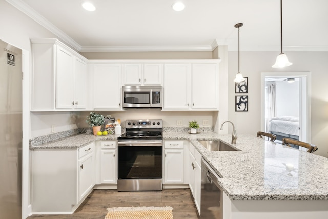 kitchen with stainless steel appliances, hanging light fixtures, sink, and white cabinets