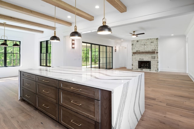 kitchen with beam ceiling, light hardwood / wood-style flooring, hanging light fixtures, and a healthy amount of sunlight