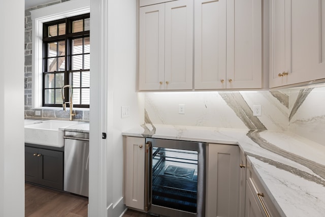 bar featuring wine cooler, light stone counters, dark hardwood / wood-style flooring, dishwasher, and sink